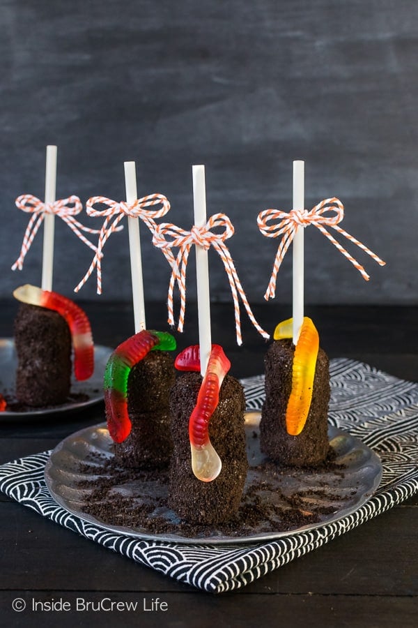 Dirt Marshmallow Pops - add cookie crumbs and gummy worms to chocolate covered marshmallow pops for a fun dirt dessert. Easy no bake recipe for Halloween or school parties! #halloween #dirtdessert #marshmallowpops #chocolatecoveredmarshmallows #gummyworms #halloween #nobakedessert #chocolate #marshmallows