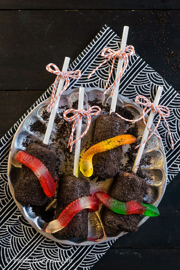 Dirt Marshmallow Pops - chocolate covered marshmallows covered in Oreo cookie crumbs and a gummy worm makes a fun and easy Halloween treat. Make this no bake recipe for school Halloween parties this year. #halloween #dirtdessert #marshmallowpops #chocolatecoveredmarshmallows #gummyworms #halloween #nobakedessert #chocolate #marshmallows