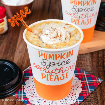 A pumpkin latte with whipped cream in a paper cup.