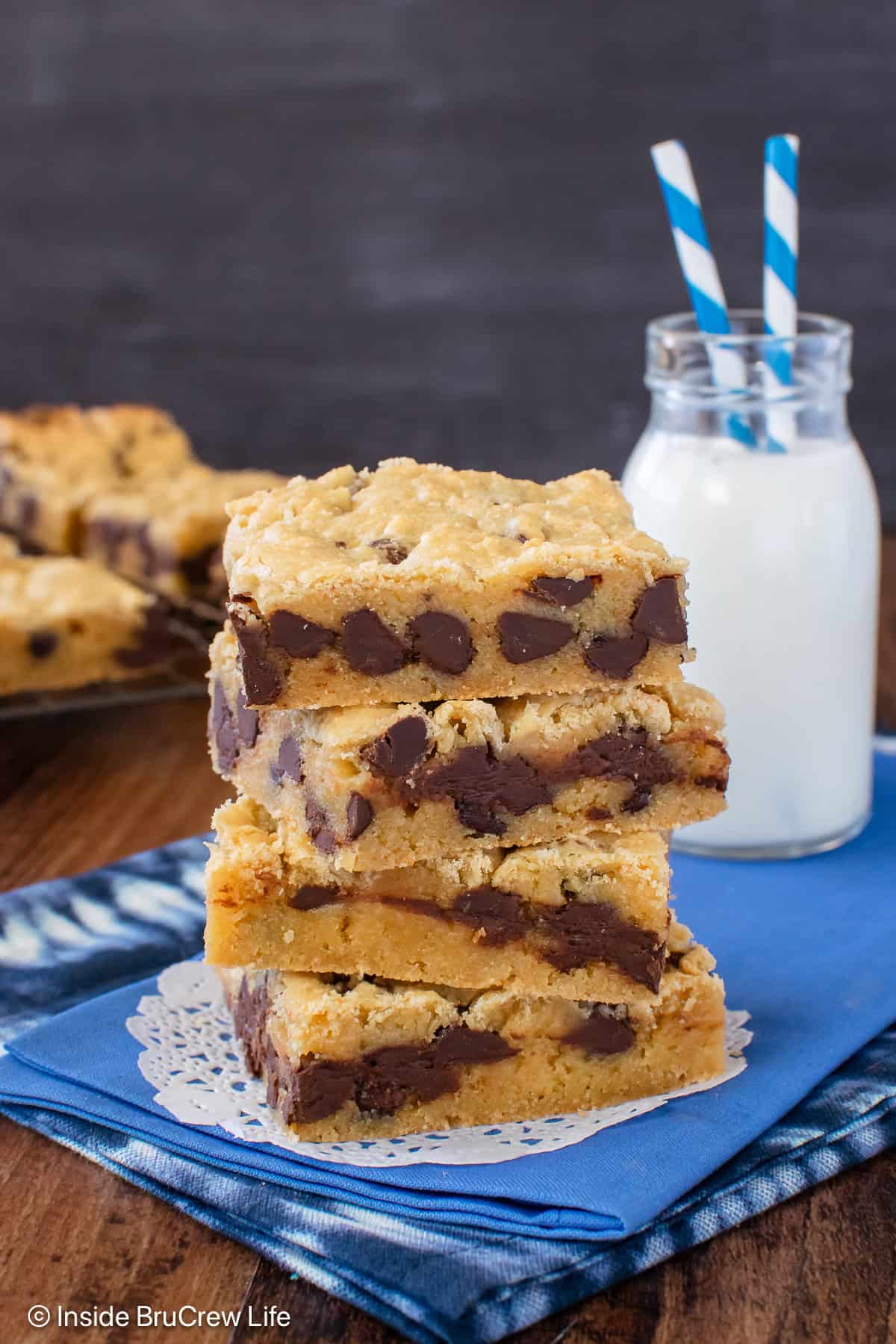 Four congo bars stacked on a blue towel with a glass of milk.