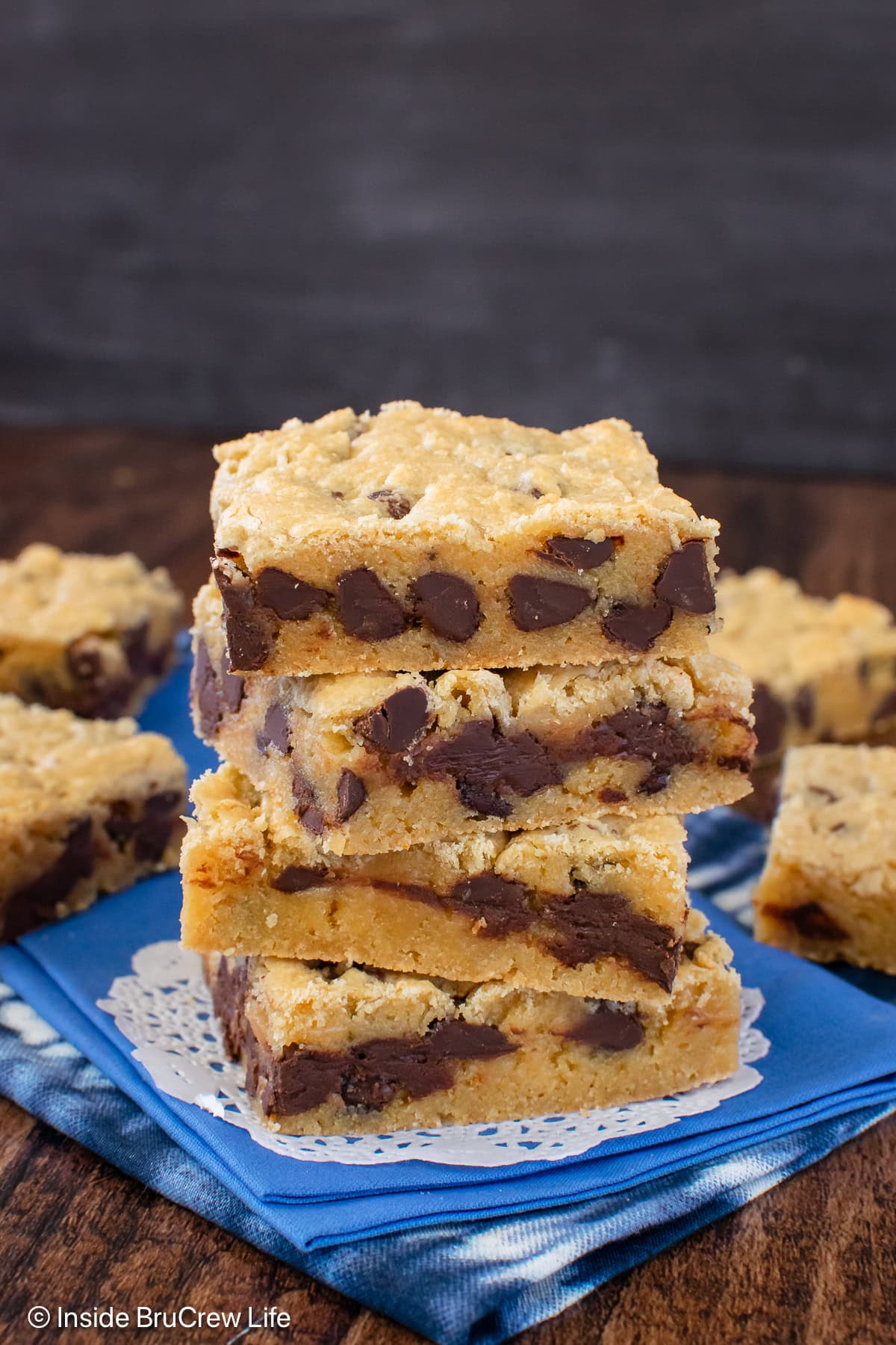 Four squares of chocolate chip blondies on a blue towel.