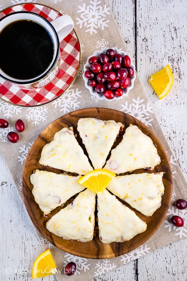 Overhead picture of a brown plate with glazed cranberry orange scones arranged on it.