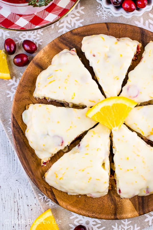 Overhead picture of a wooden plate with cranberry scones with an orange glaze on it.