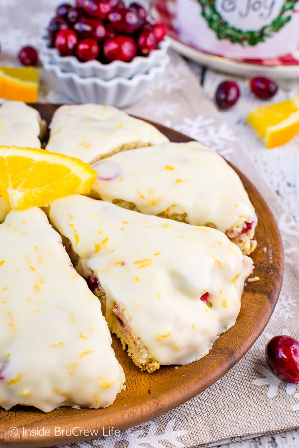 Cranberry scones topped with an orange glaze on a brown plate.