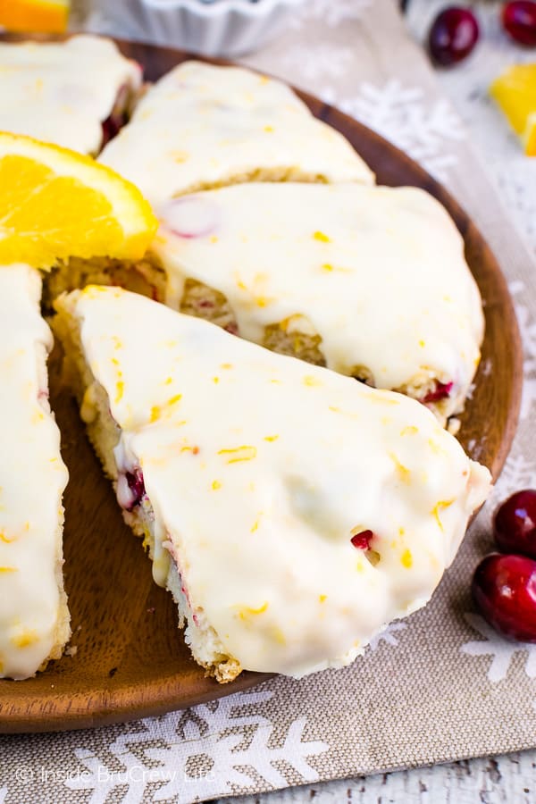 Close up of a cranberry orange scone on a brown plate topped with orange glaze.