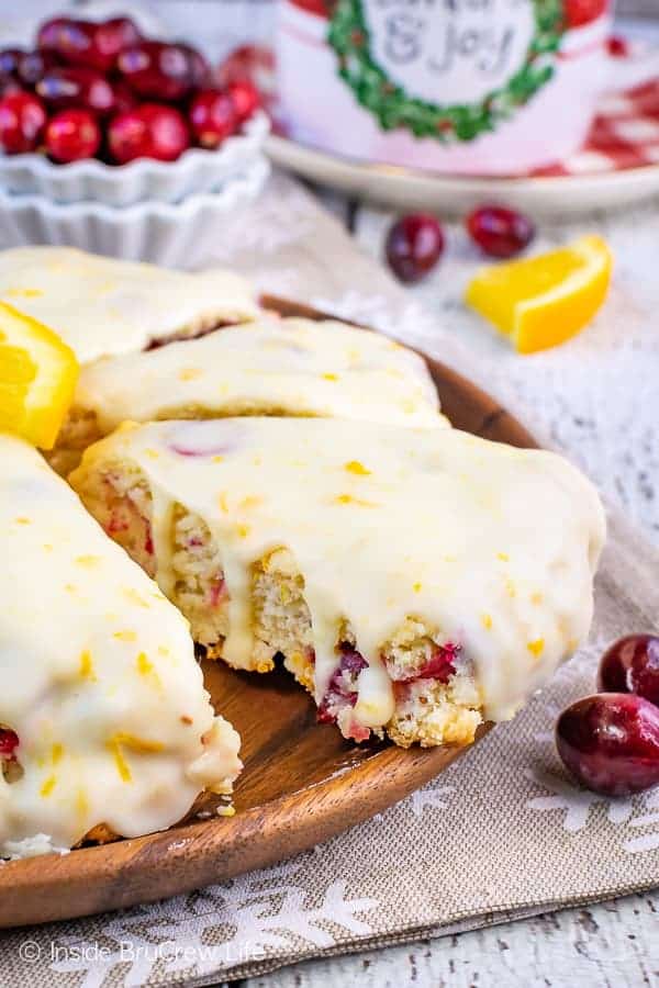 Cranberry Orange Scones on a brown board topped with an orange glaze.