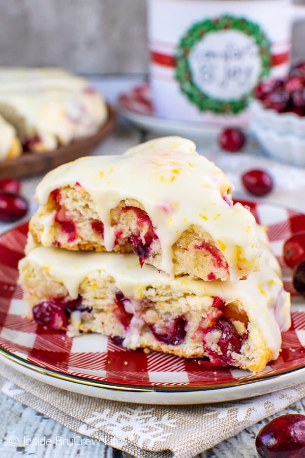 A red and white checkered plate with two cranberry orange scones stacked on it.