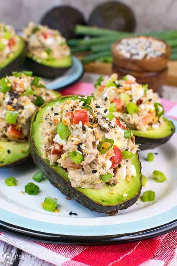 Three avocados on a white plate stuffed with the Everything Tuna Salad