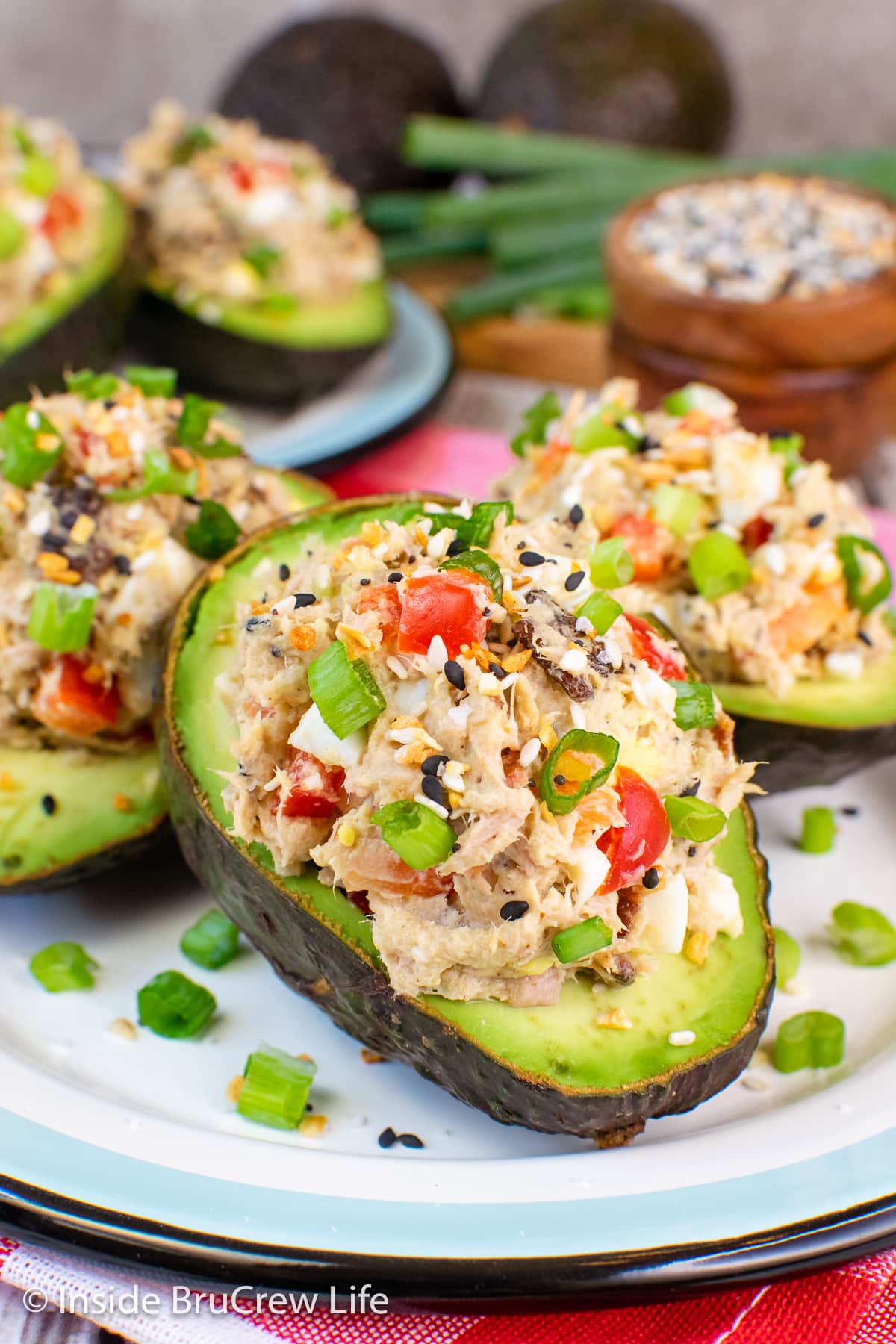 Three avocado halves stuffed with tuna salad on a plate.