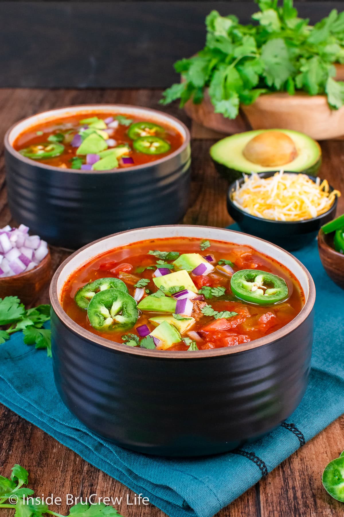 Two bowls of chili with toppings.