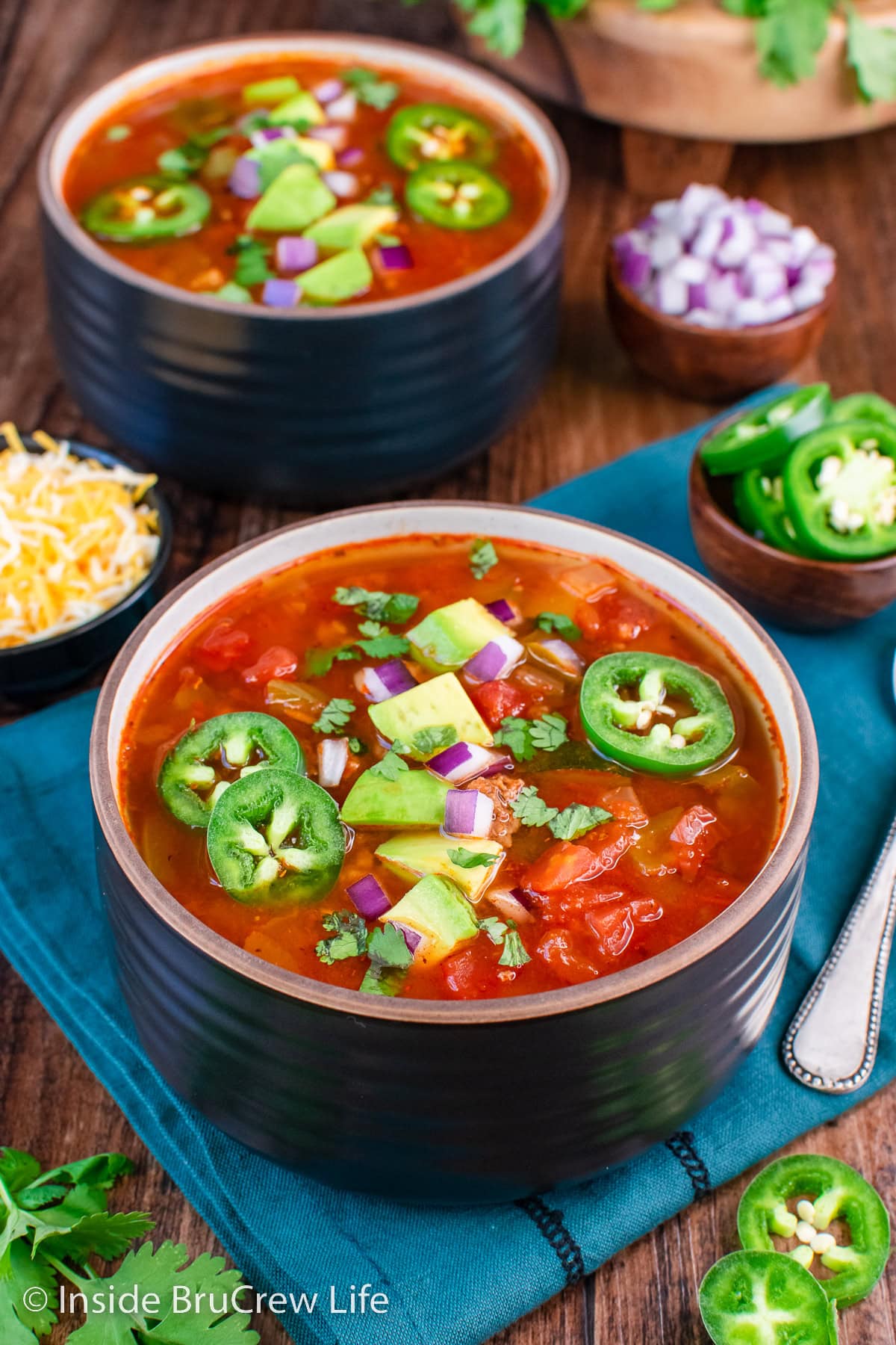 A bowl of low carb chili topped with jalapenos and avocado chunks.