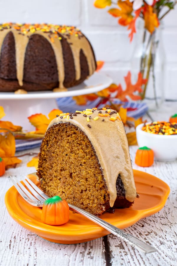  An orange plate with a slice of pumpkin cake topped with maple glaze on it.