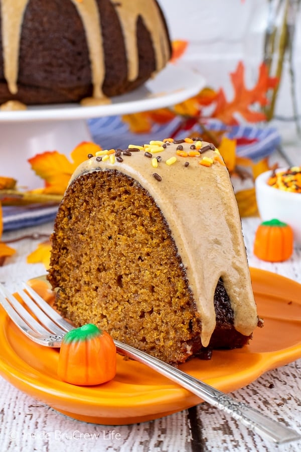 An orange plate with a slice of pumpkin bundt cake topped with maple glaze.