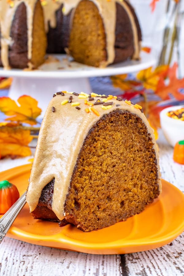 A slice of pumpkin bundt cake with maple glaze on an orange plate.