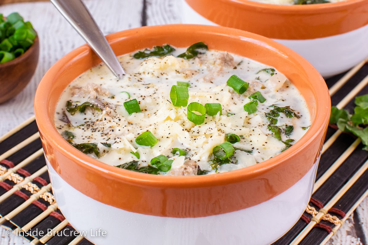 A bowl filled with a creamy sausage and kale soup.