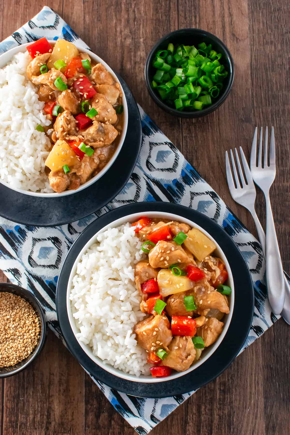 White rice and sweet and sour crockpot chicken served in white bowls.