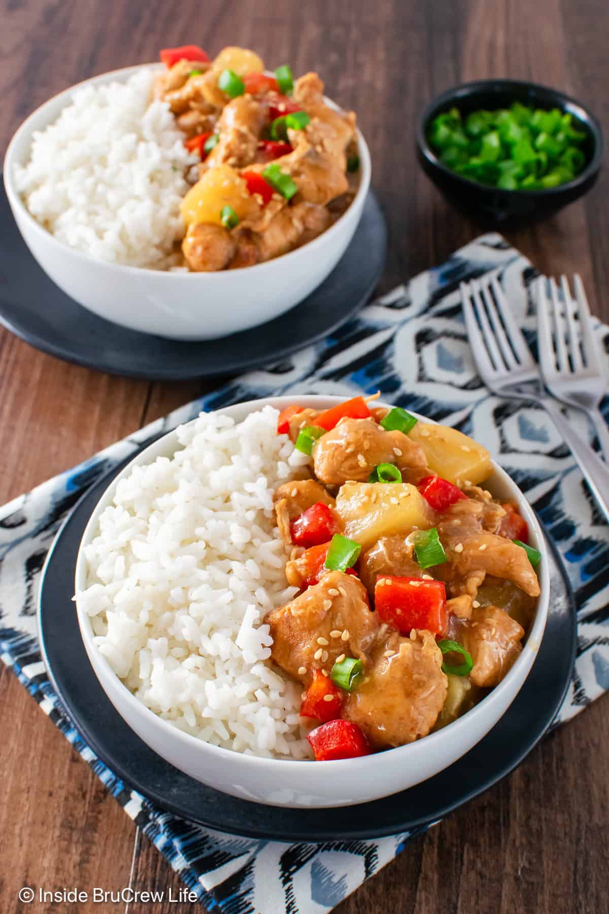 White rice and sweet and sour crockpot chicken served in white bowls.