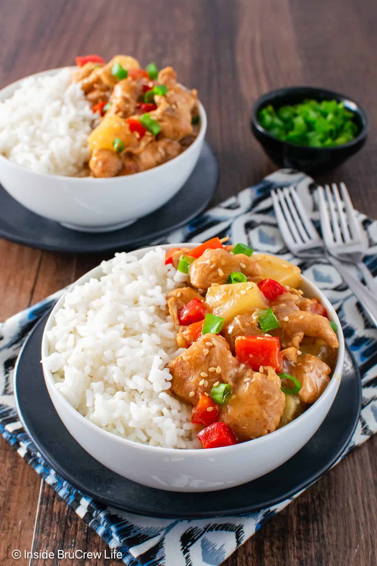 Two white bowls filled with sweet and sour chicken and white rice.