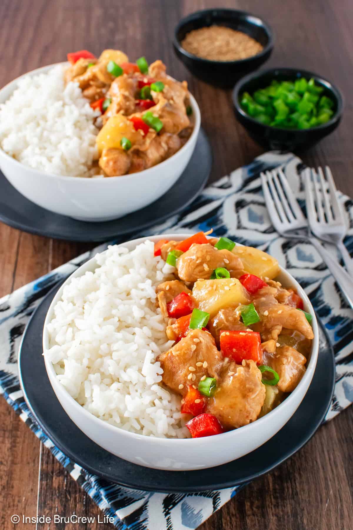 Two white bowls filled with sweet and sour chicken and white rice.