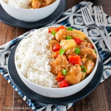 A white bowl filled with rice and sweet and sour chicken.