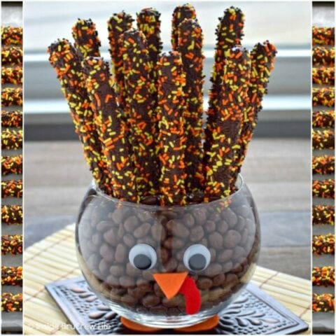 A clear jar decorated to look like a turkey and filled with chocolate covered pretzels