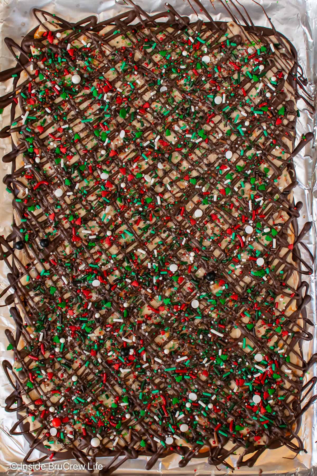 A tray of caramel chocolate pretzel bark topped with red and green sprinkles.