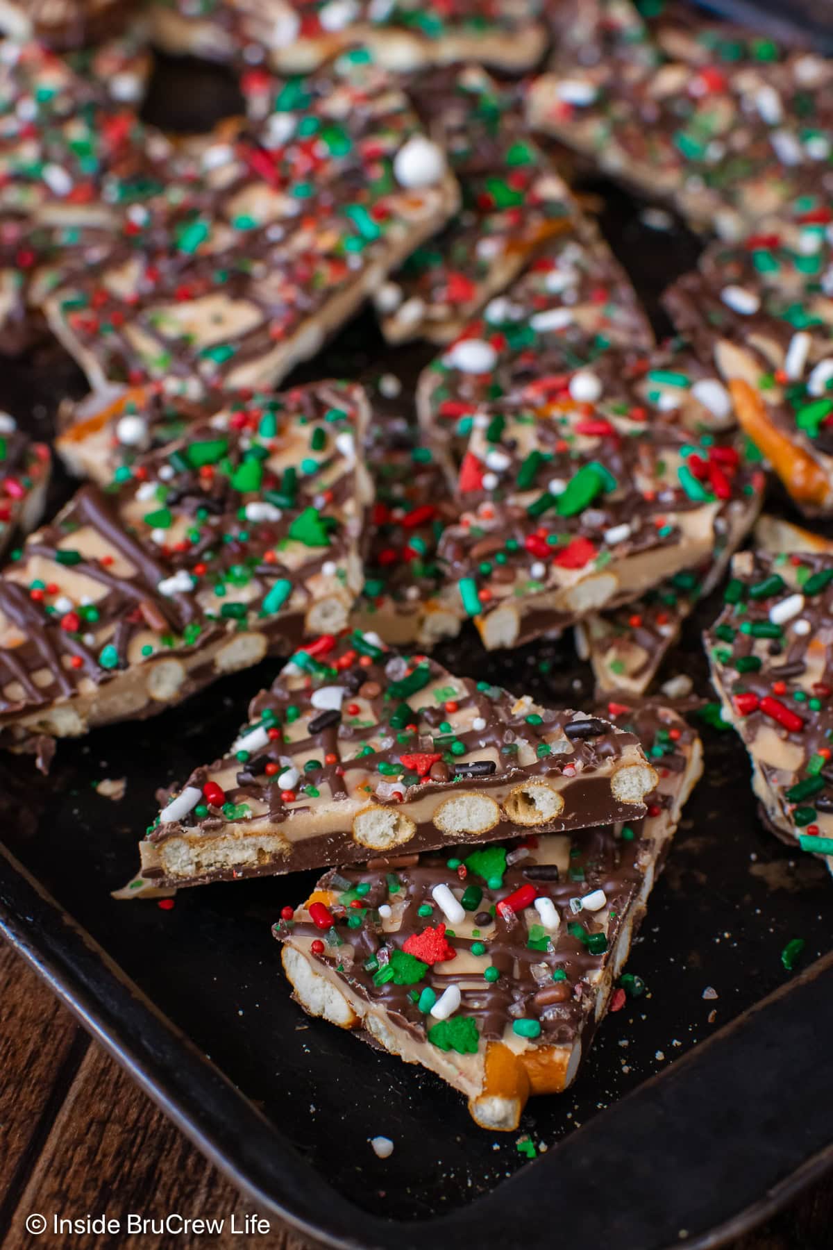 Pieces of chocolate pretzel bark on a dark metal tray.