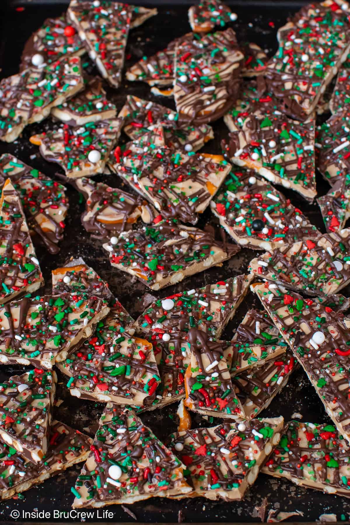 Pieces of chocolate pretzel bark on a dark metal tray.