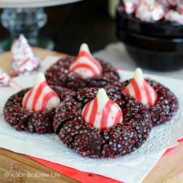 Four chocolate kiss cookies with red and white sugar and a candy cane kiss.