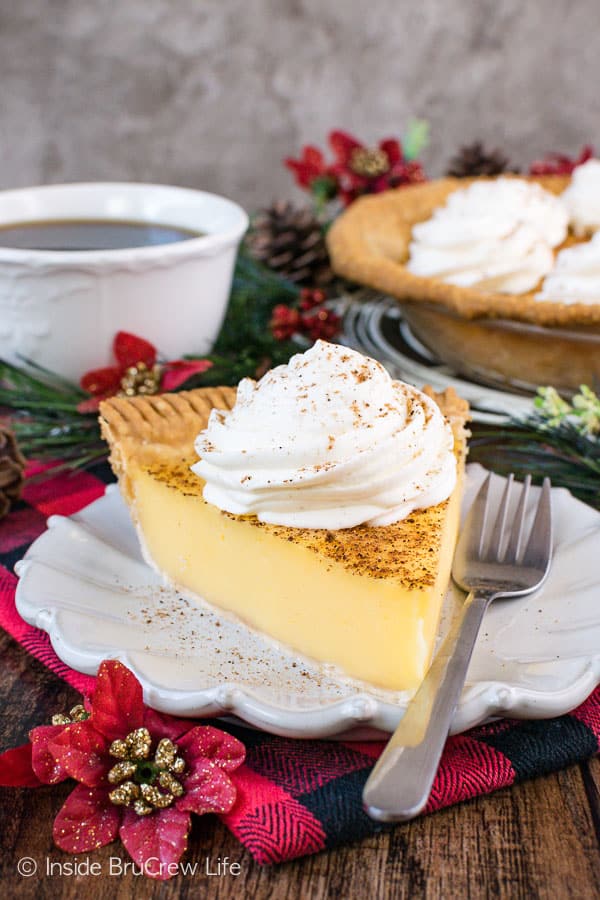 A slice of eggnog cream pie with eggnog whipped cream on a white plate