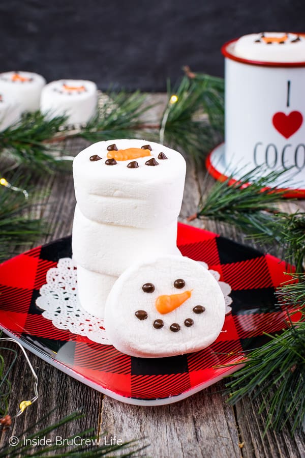 A stack of Marshmallow Snowmen heads on a black and red plaid plate.