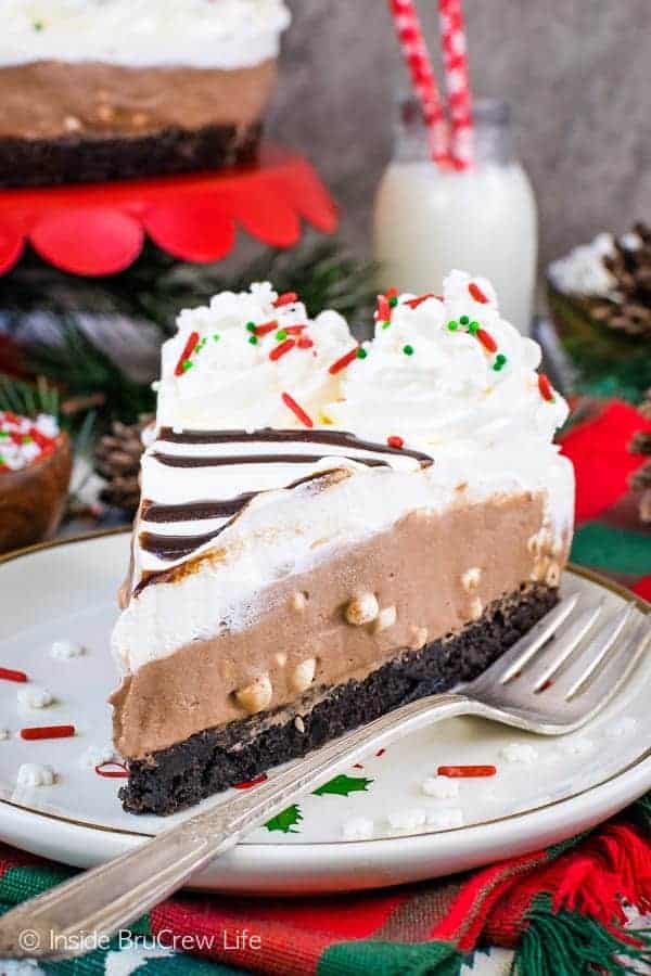 A slice of hot cocoa cheesecake with a brownie crust on a plate.