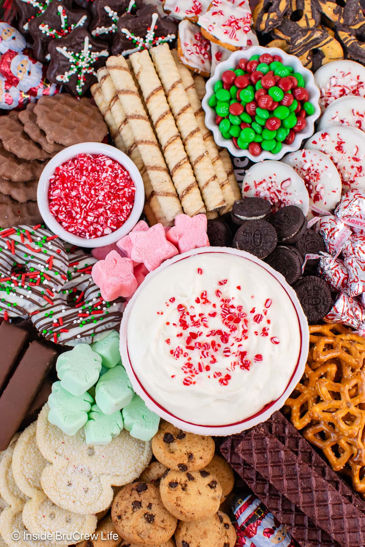 A tray of cookies with a bowl of peppermint dip in the middle.