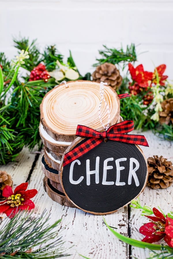 Rustic Wood Ornaments - painted wood ornaments with a red and black checkered ribbon. Easy wood craft to make and hang on your Christmas tree this year. #rustic #woodornaments #raedunninspired #farmhousedecor #woodcrafts #christmastreeornaments