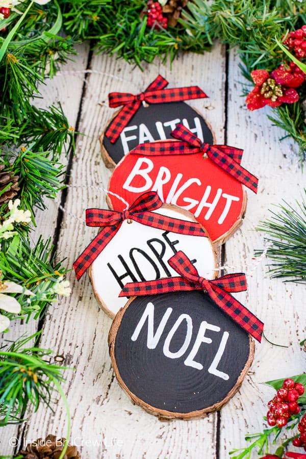 Rustic Wood Ornaments - wood ornaments painted with red, white, and black and holiday words. Easy wood craft to make and hang on your tree or garland. #rustic #woodornaments #raedunninspired #farmhousedecor #woodcrafts #christmastreeornaments