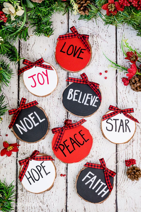 Rustic Wood Ornaments - holiday words painted on wood ornaments with a red and black checkered ribbon. Easy farm house decor wood ornament. #rustic #woodornaments #raedunninspired #farmhousedecor #woodcrafts #christmastreeornaments