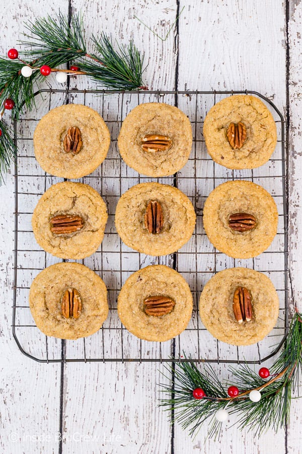 An overhead picture of a gray wire cooling rack with maple cookies stacked on it.