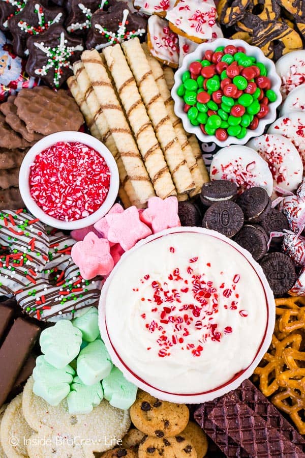An assortment of Christmas cookies with a bowl of White Chocolate Peppermint Cheesecake Dip.