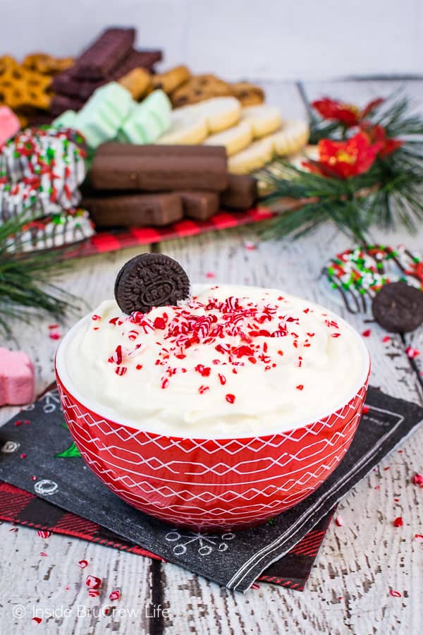 A bowl of White Chocolate Peppermint Cheesecake Dip with cookies in the background.