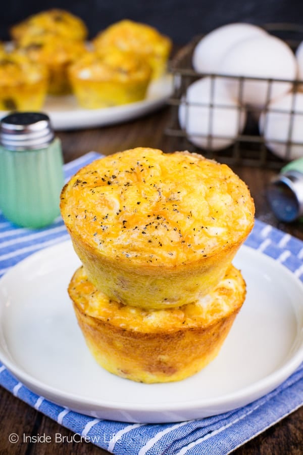 Two ham and cheese egg muffins stacked on top of each other on a white plate