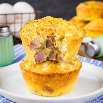 Two egg muffin cups made with ham and cheese stacked on a white plate