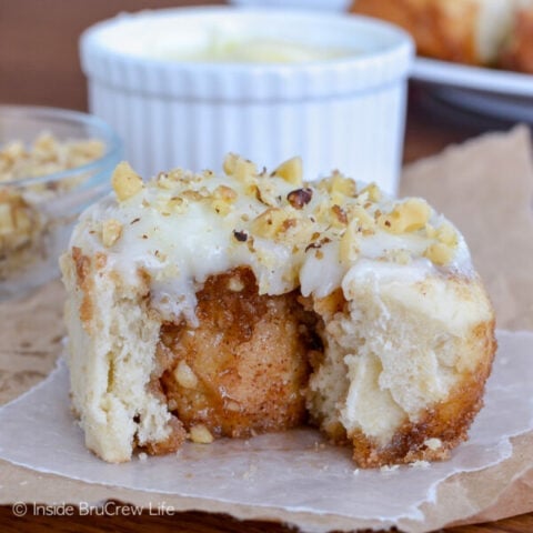 A banana nut cinnamon roll with a bite out of it on parchment paper.