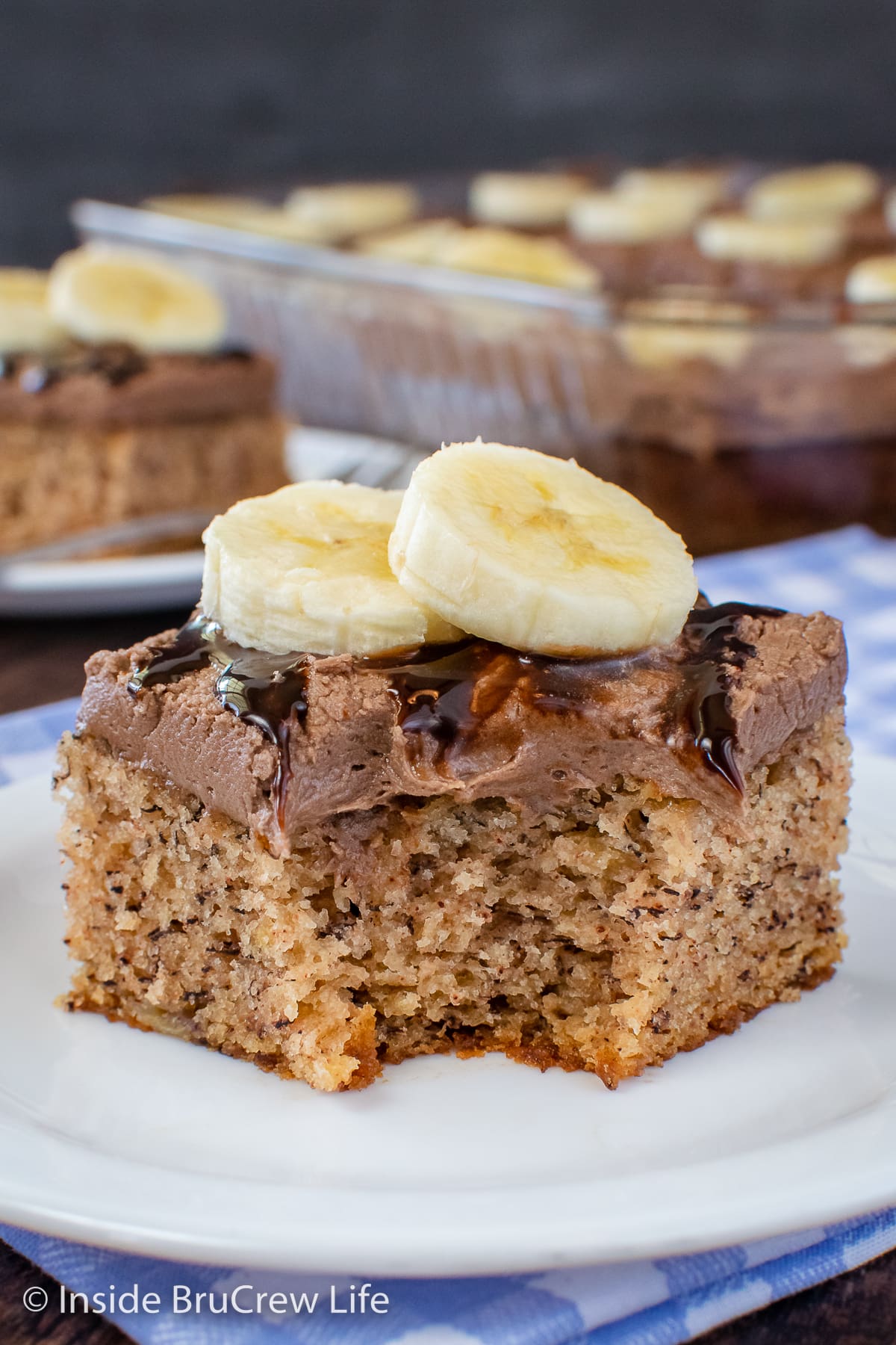 A white plate with a cake square on it and a bite missing from the front.