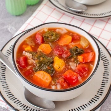 A bowl of cabbage vegetable soup with a spoon beside it.