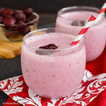 Two glasses filled with a cherry banana smoothie and a paper straw.