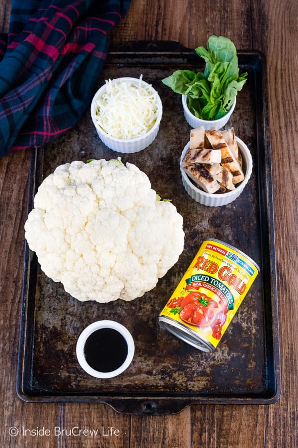 An overhead picture of a sheet pan with bowls of ingredients needed to make chicken cauliflower nachos.