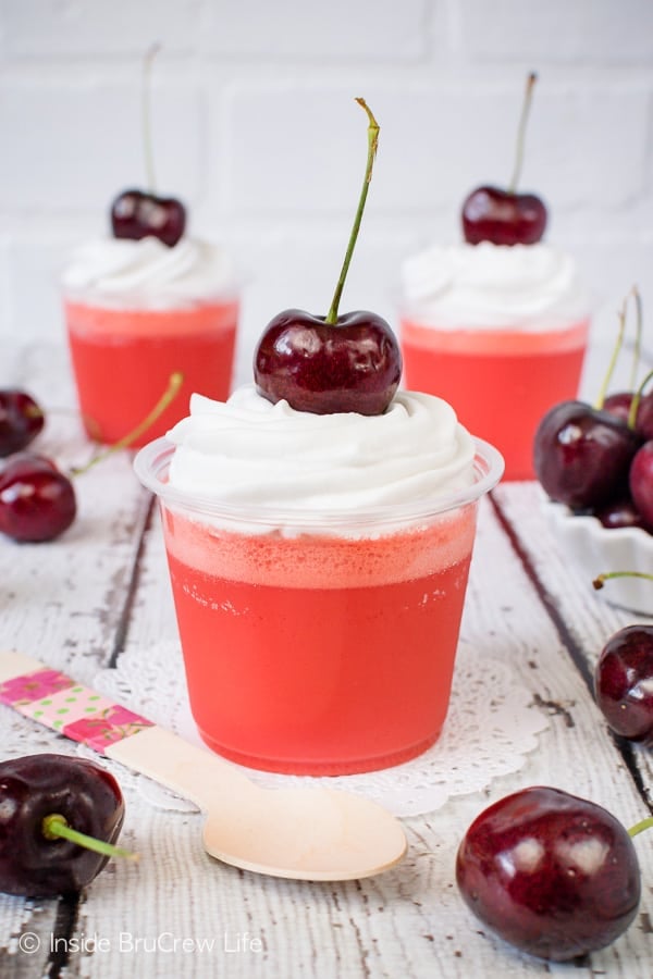 Close up of a clear cup filled with low carb cherry jello parfait on a white background