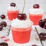 Clear cups filled with low carb cherry jello and topped with whipped cream and a cherry