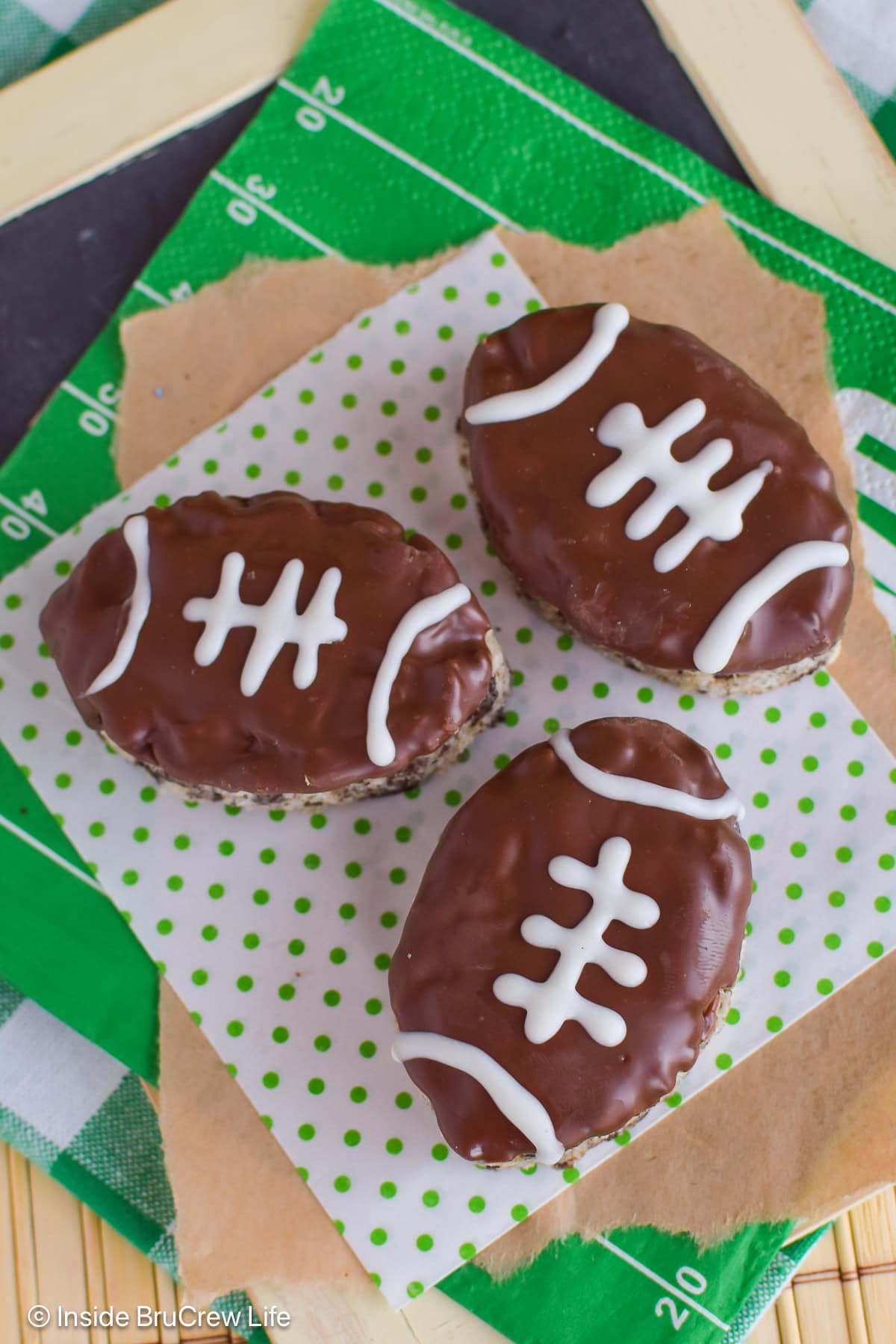 Three no bake football treats lying on a board.