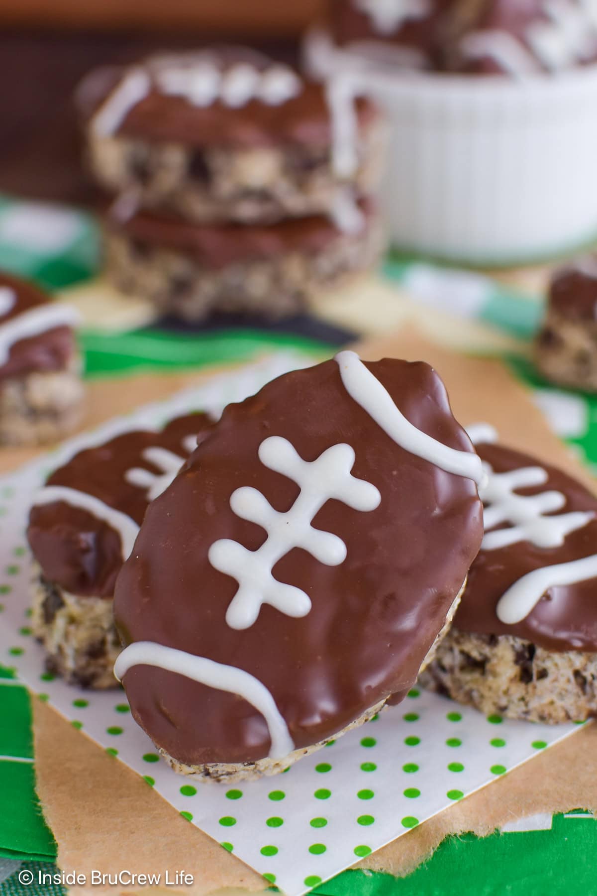 Three rice krispie footballs lying on a green and white napkin.